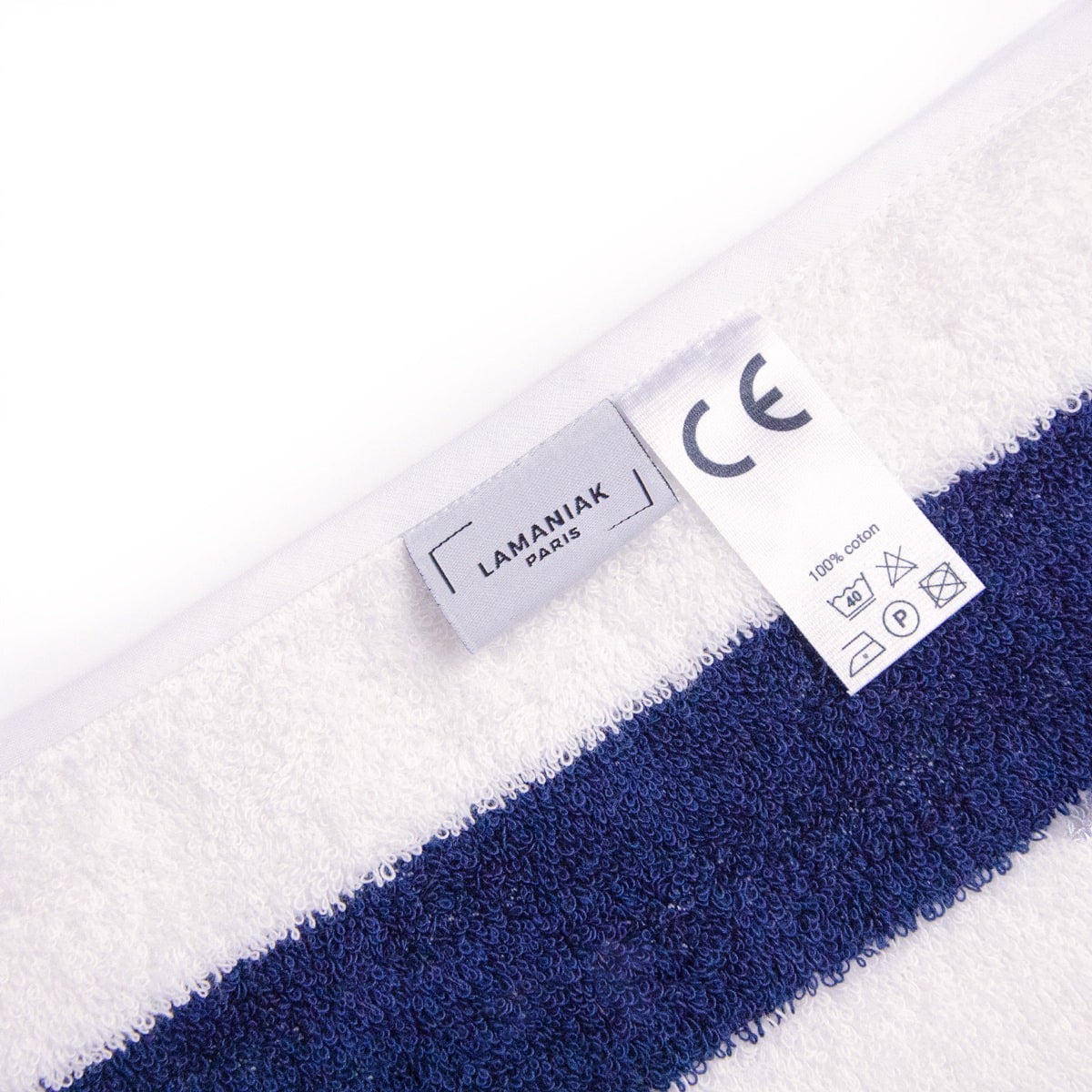 Détail étiquette de la serviette intemporelle de LAMANIAK inspirée de DEAUVILLE avec ses rayures bleu marine et blanche fabriquée en 100% coton en FRANCE 